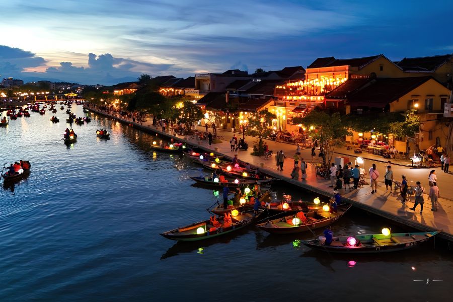 Warm lantern lights illuminating historic traditional shophouses along the river in Hoi An