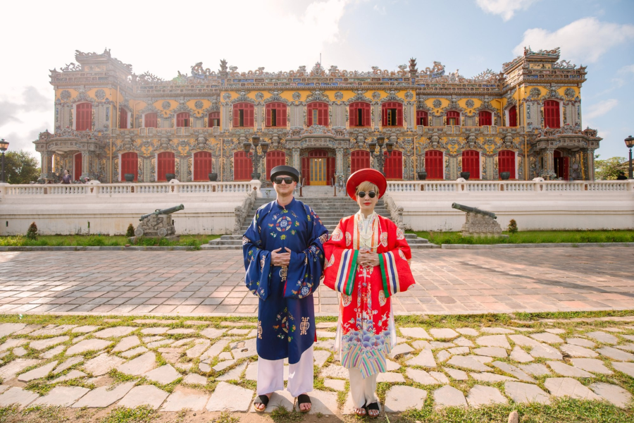 Family dressed in traditional royal silk robes exploring the ancient courtyards and stone gates of the Imperial Citadel in Hue