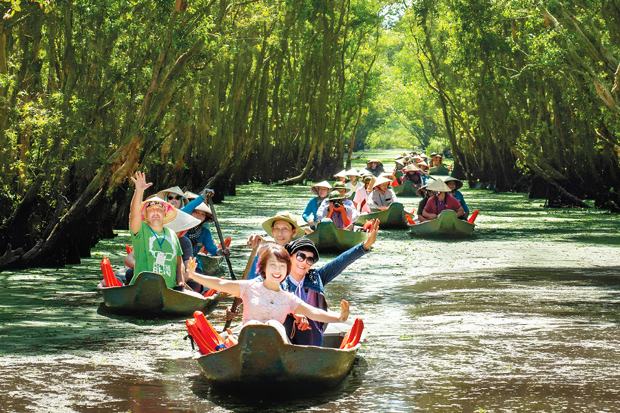 Families enjoying a shaded wooden sampan boat ride along narrow coconut canals in the tropical Mekong Delta