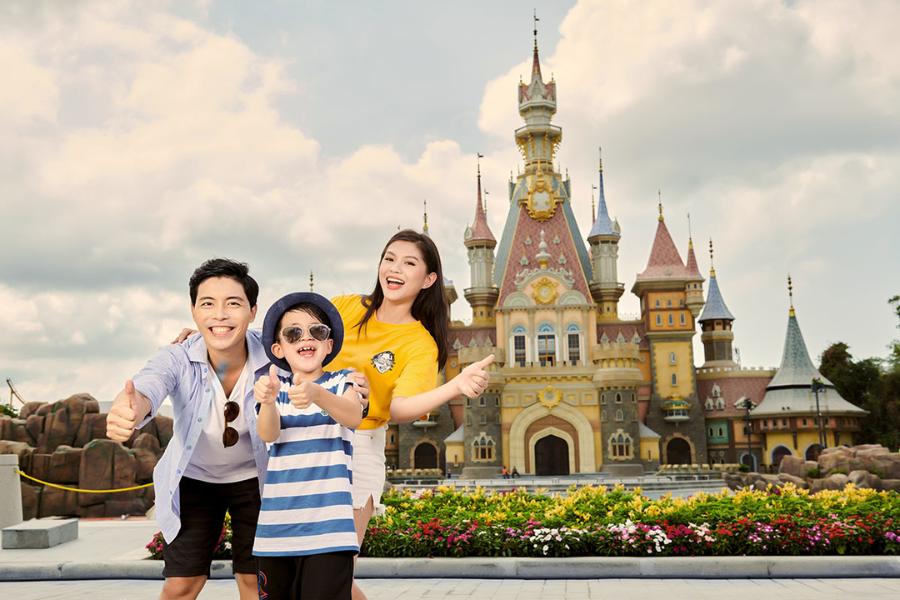 Family with happy children walking past fairytale castles and enjoying fun outdoor rides at VinWonders theme park in Phu Quoc, one of the best places to visit in Vietnam for families