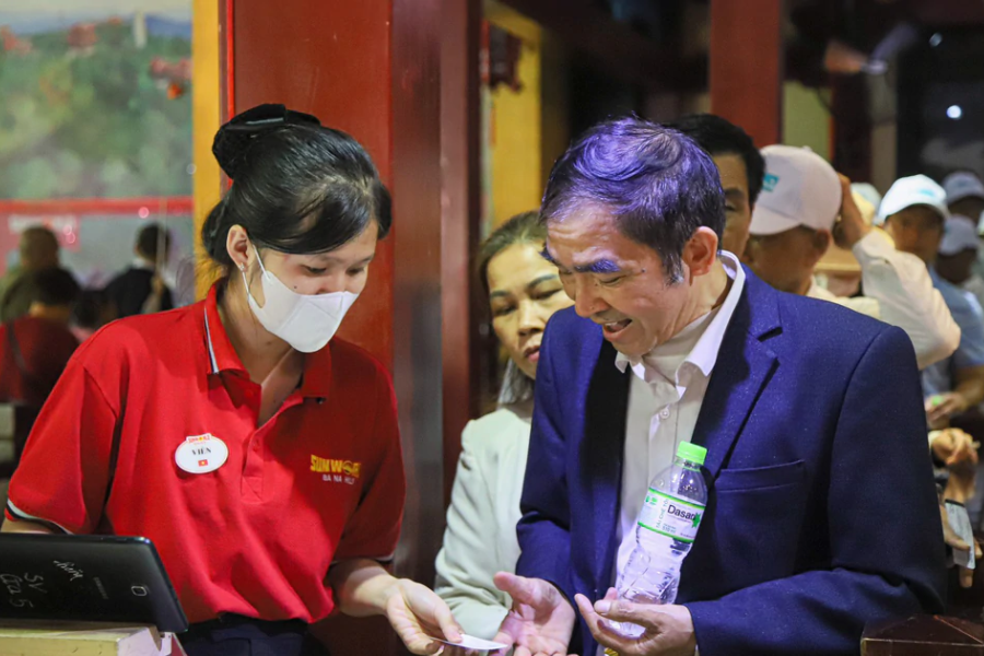 Visitor scanning an electronic mobile QR voucher on a smartphone screen at the entry turnstile of Ba Na Hills in Da Nang