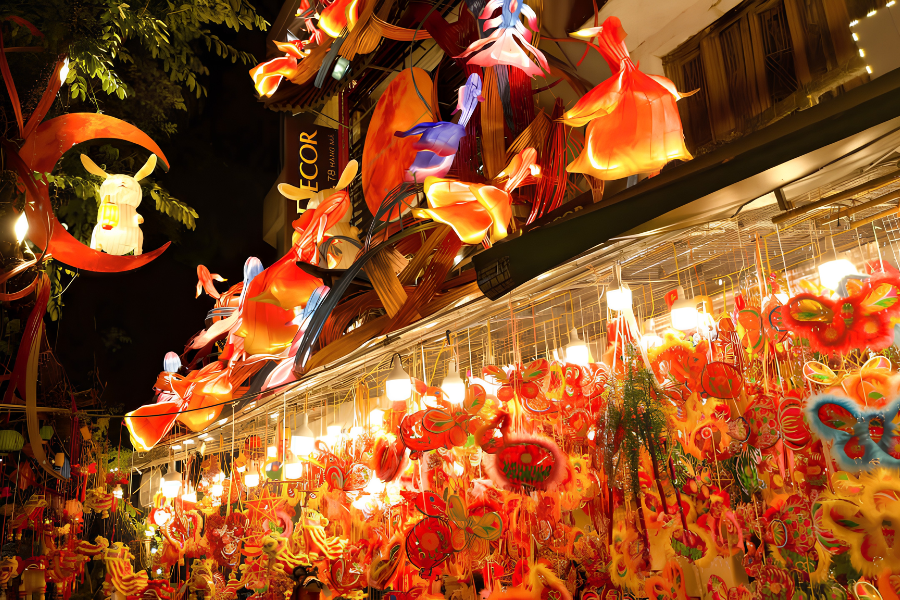 Bright red handmade star lanterns and traditional paper masks displayed on Hang Ma street in Hanoi.