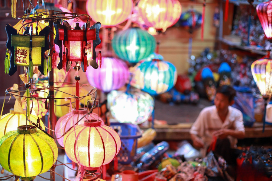 Elderly Vietnamese master artisan handcrafting traditional bamboo and silk Hoi An lantern frame in heritage workshop
