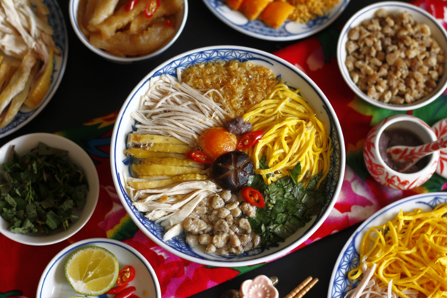 Artistically assembled bowl of delicate Hanoi noodle soup topped with shredded chicken, thin egg ribbons, julienned pork sausage, and crystal-clear broth