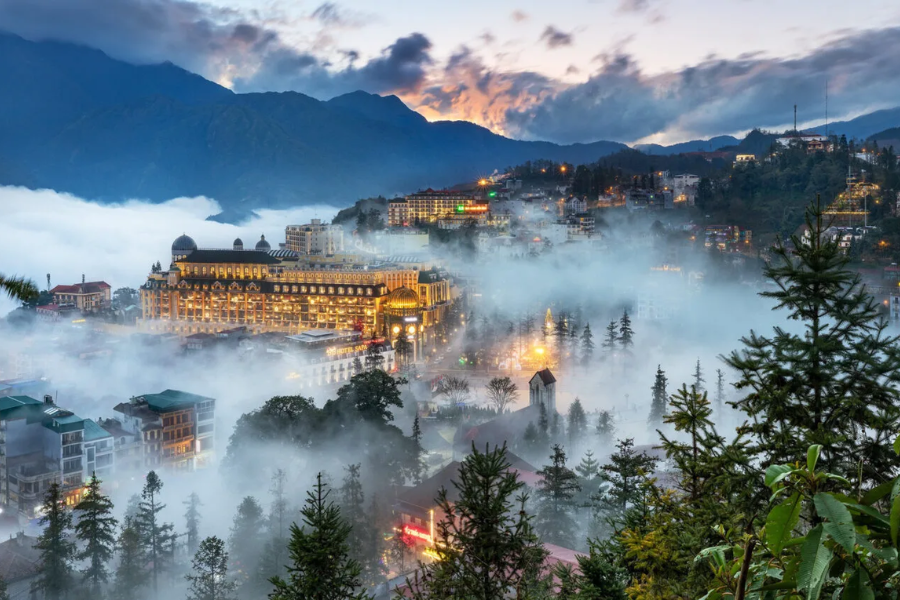 Scenic mountain valley covered in misty morning clouds with luxury eco-lodges overlooking rice terraces in Sapa