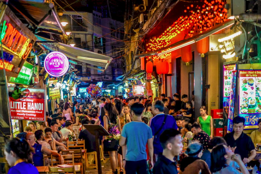 Cold local Vietnamese craft beer and roasted lotus seed tapas served at dusk on an open-air trackside cafe terrace in Hanoi