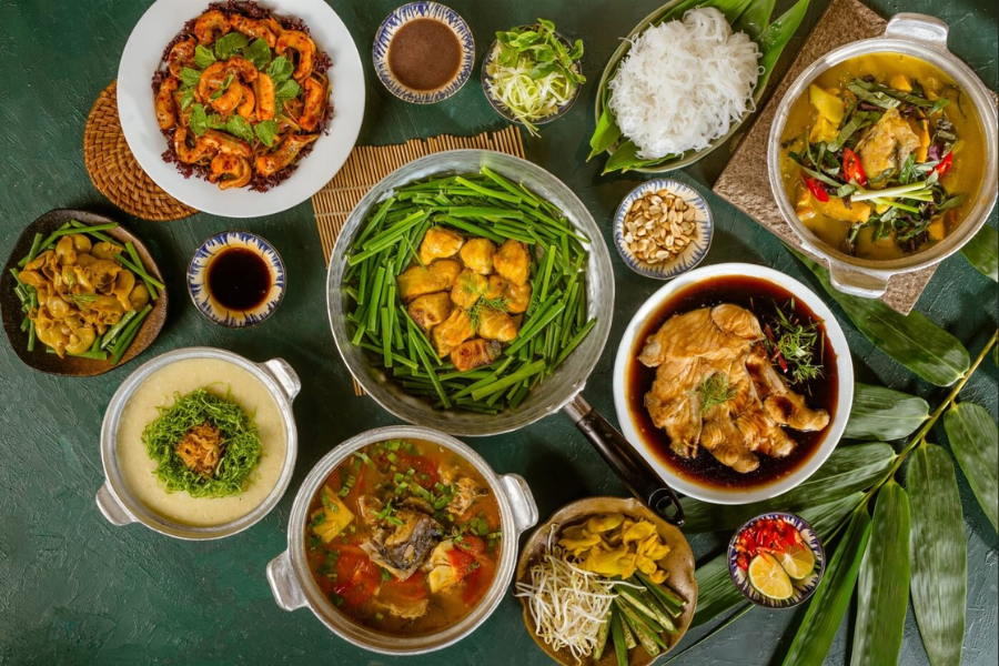 Sizzling cast-iron skillet of golden turmeric fish fillets tossed with generous amounts of fresh green dill and scallions in a heritage restaurant in Hanoi
