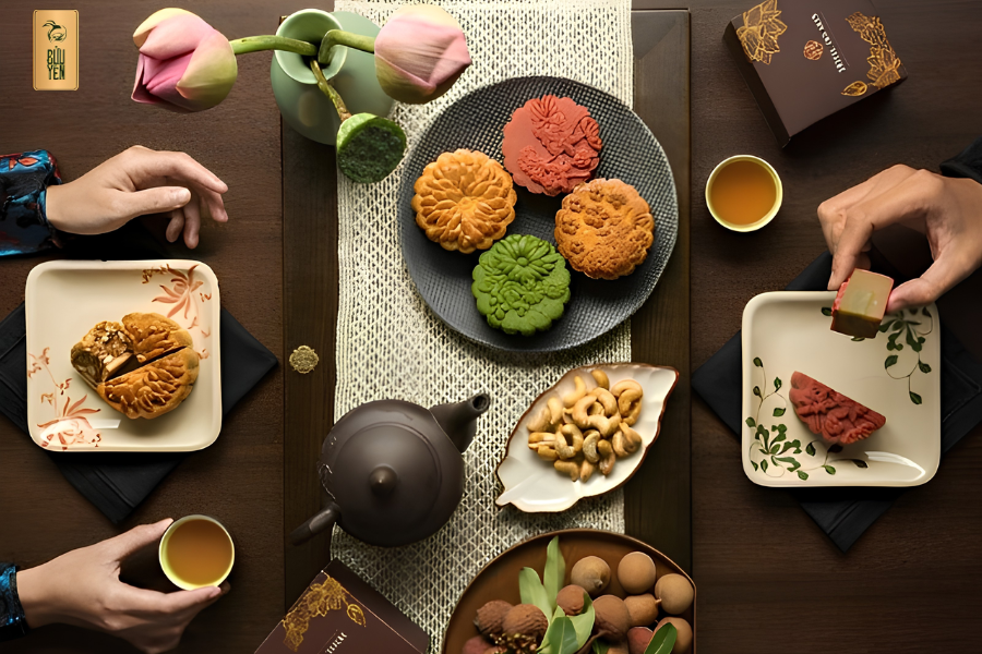 Artisanal baked moon cake sliced on a ceramic plate beside a hot pot of Vietnamese lotus tea