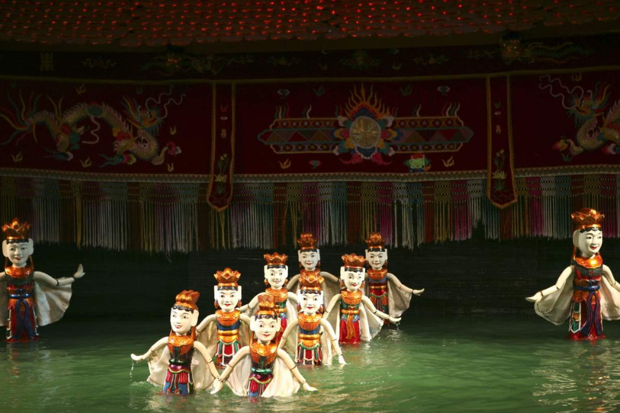 Excited young children watching traditional wooden water puppets dance on water at a theater in Hanoi, one of the best places to visit in Vietnam for families