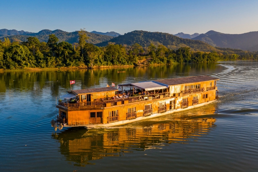 Boat travelling along the Mekong River in Laos with mountains in the background