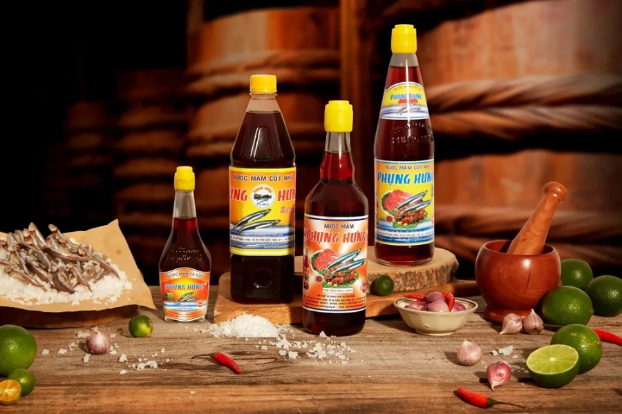 Glass bottles of amber-colored artisanal fish sauce paired with glass jars of sun-dried whole black peppercorns from Phu Quoc Island