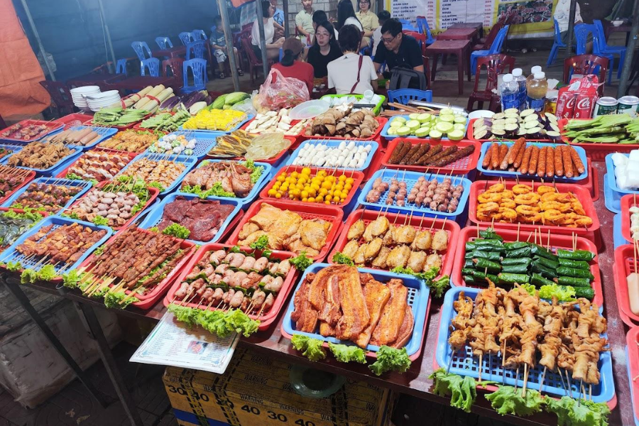 Skewers of pork rolled with wild vegetables and young bamboo sticky rice grilling over glowing charcoal at Sapa Night Market