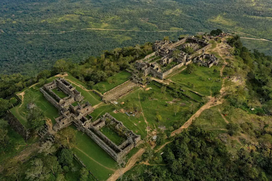 Ancient stone pavilion perched on the sheer mountain cliff edge of Preah Vihear overlooking vast green plains beneath a bright sky