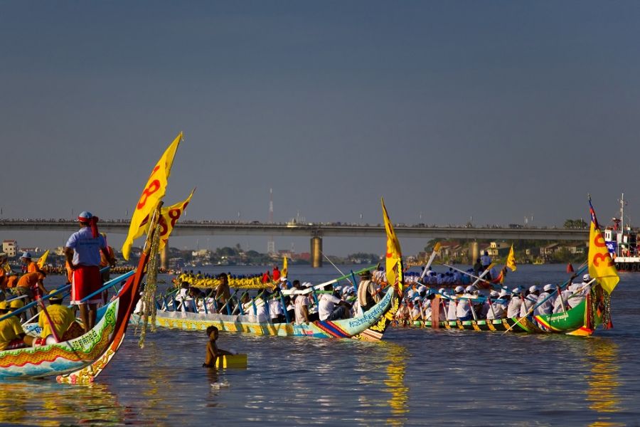 Colorful longboat racing teams rowing fiercely along the Tonle Sap riverbank in Phnom Penh during the annual Water Festival