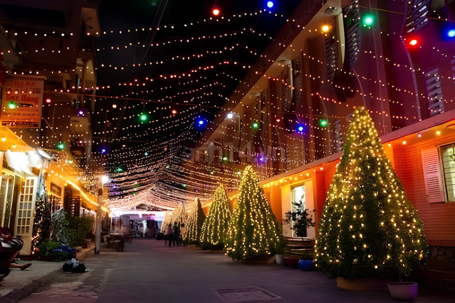 A dazzling overhead tunnel of vibrant purple and green LED lights spanning across houses in a Saigon Catholic neighborhood during Christmas Eve