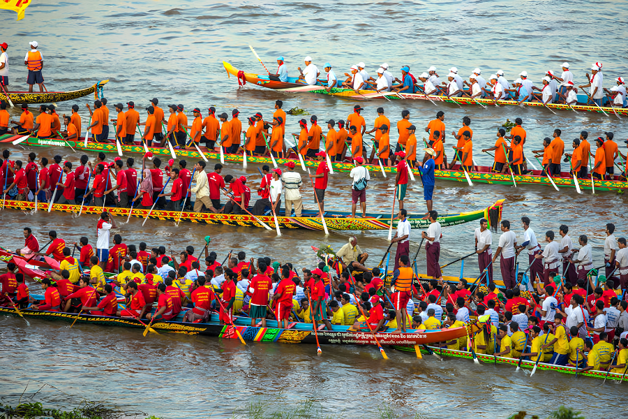 Long wooden racing dragon boats powered by dozens of synchronized rowers competing on the Tonle Sap River during Bon Om Touk in Phnom Penh
