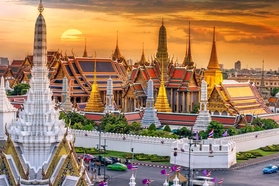 Gilded spires and colorful mosaic stupas of the Grand Palace and Wat Phra Kaew at sunset in Bangkok