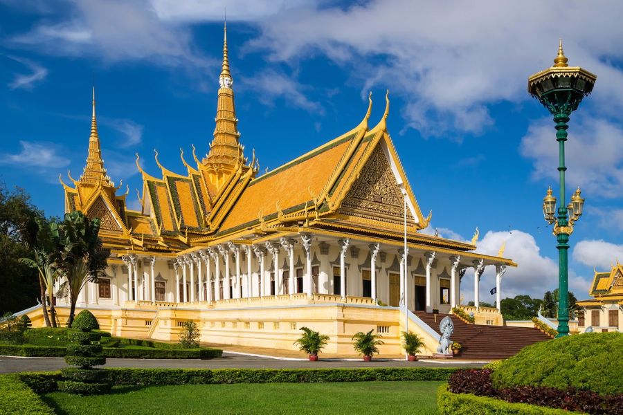 Intricate golden spires and classic Khmer-style roofs of the Royal Palace complex under a clear blue sky in Phnom Penh