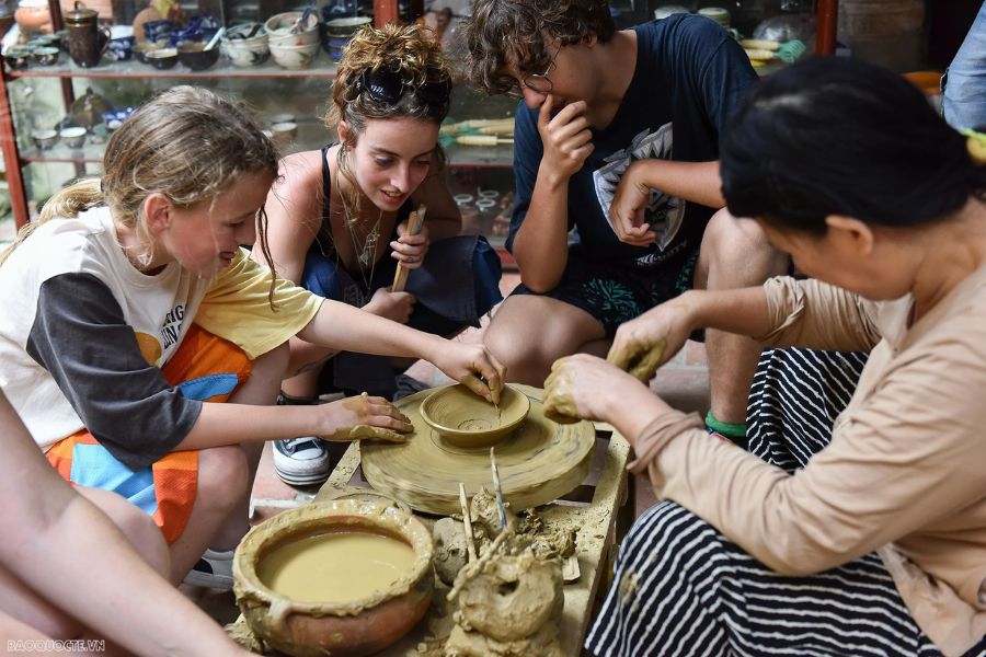 Local potter shaping a clay bowl on a manual foot-spinning wheel at Thanh Ha Pottery Village in Hoi An