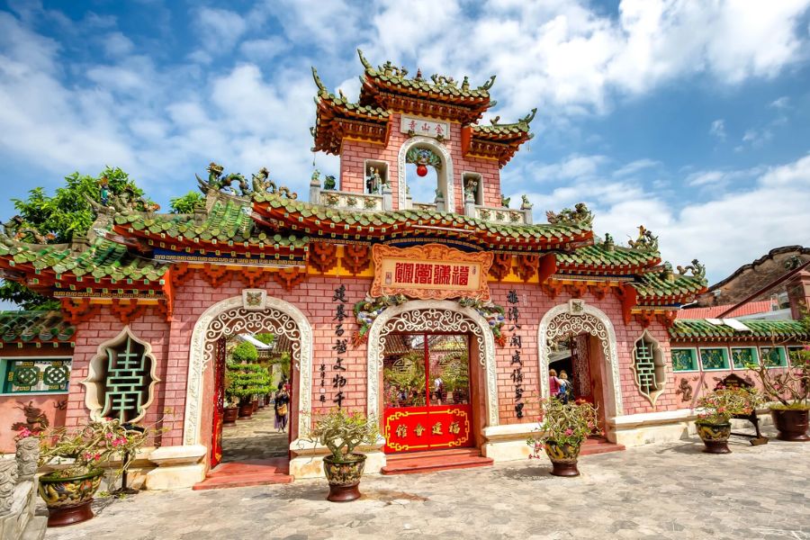 Ornate dragon statues and large hanging spiral incense coils inside the Fujian Assembly Hall in Hoi An