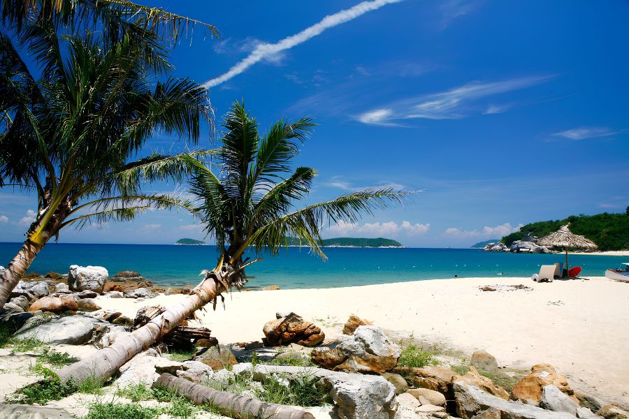 Speedboat anchored in turquoise waters near granite cliffs and lush green hills of the Cham Islands