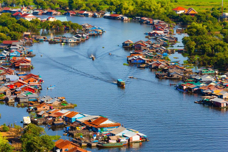 Traditional wooden stilted houses and small fishing canoes floating on the calm waters of Tonle Sap Lake in Cambodia