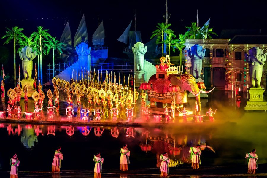 Hundreds of dancers in glowing white Ao Dai performing on an outdoor illuminated water stage at Hoi An Memories show