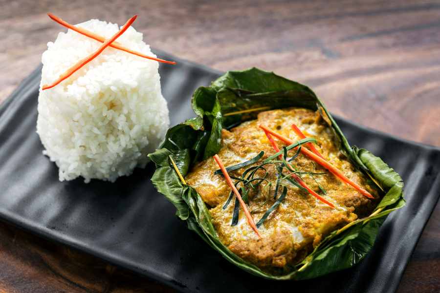 Traditional Cambodian Fish Amok steamed in a folded banana leaf cup topped with thick coconut cream and sliced red chili