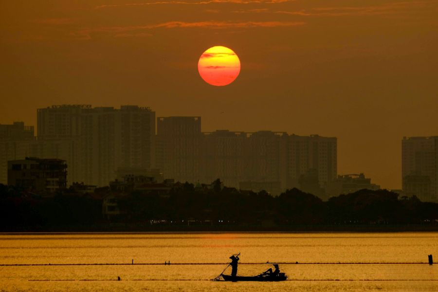Calm reflective waters of West Lake in Hanoi at sunset against an amber sky