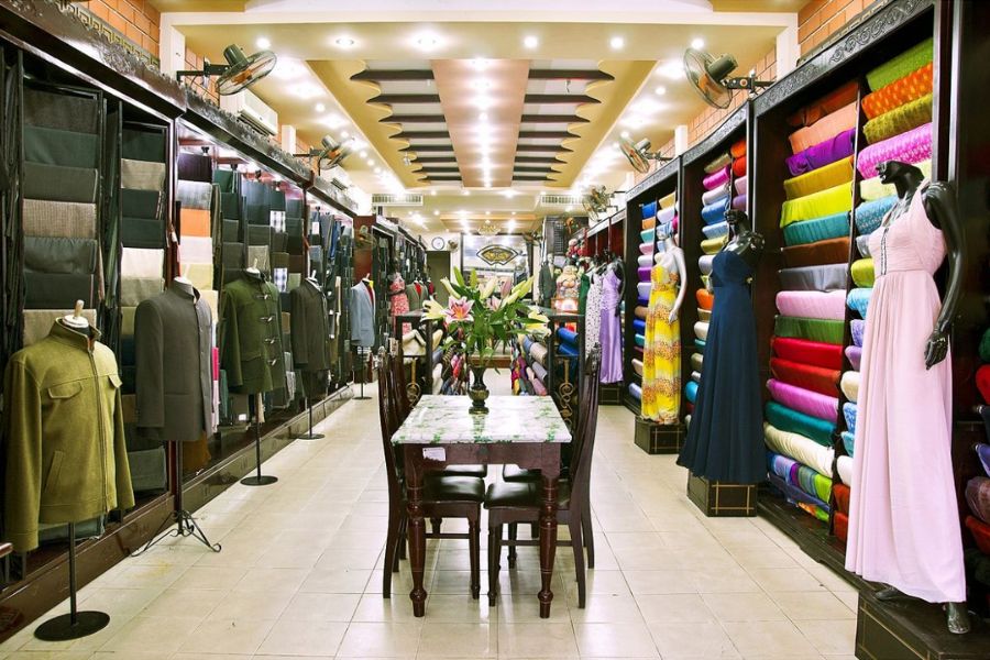 Fabric rolls and custom clothing displayed inside a tailor shop in Hoi An Ancient Town